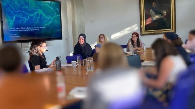 Presenters seated at a large table - blue screen behind