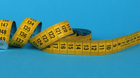 Yellow measuring tape spools across blue surface