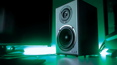 A high-quality speaker next to a computer monitor ready to share digital sound.