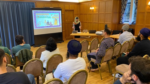 Inderpreet small at front of room by screen, with audience heads