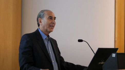 Sir David Khalili standing at lectern, mid-lecture