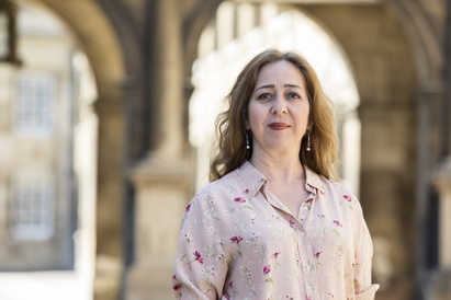 A profile photograph of Dr Vanessa Paloma Elbaz, with stone building behind