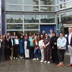 Small crowd facing the camera, facade of Faculty of Divinity behind