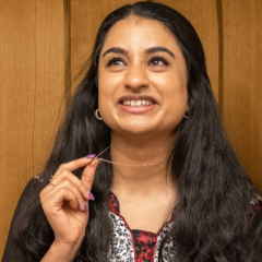 Close up photograph of Hina, gazing upward. To her right, an abstract design with gold stars on turquoise background.