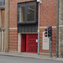 Street scene with red gates repeating the words "Wesley House"