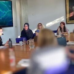 Presenters seated at a large table - blue screen behind