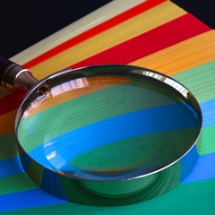 Magnifying glass rests on colourful paper