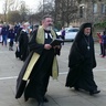 A procession of people in diverse religious garments walking towards a building 