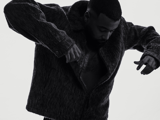 Three-quarter view of Mula B in silhouette, arms out, hands down, leaning forward  