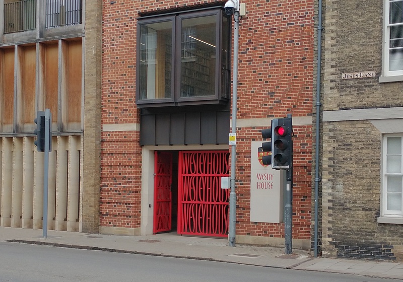 Street scene with red gates repeating the words "Wesley House"