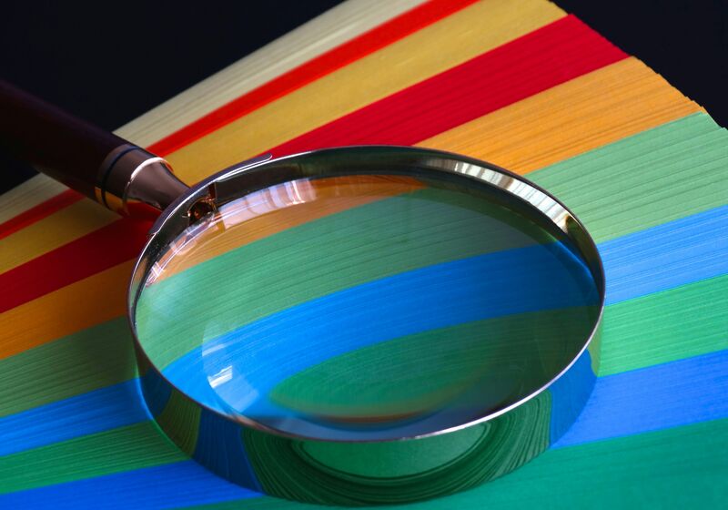 Magnifying glass rests on colourful paper