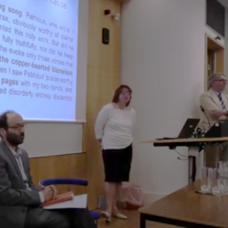 The three guests seated in front of a slide, Dr Lefteratou standing at lectern, Professor Van Kooten chairing questions. 