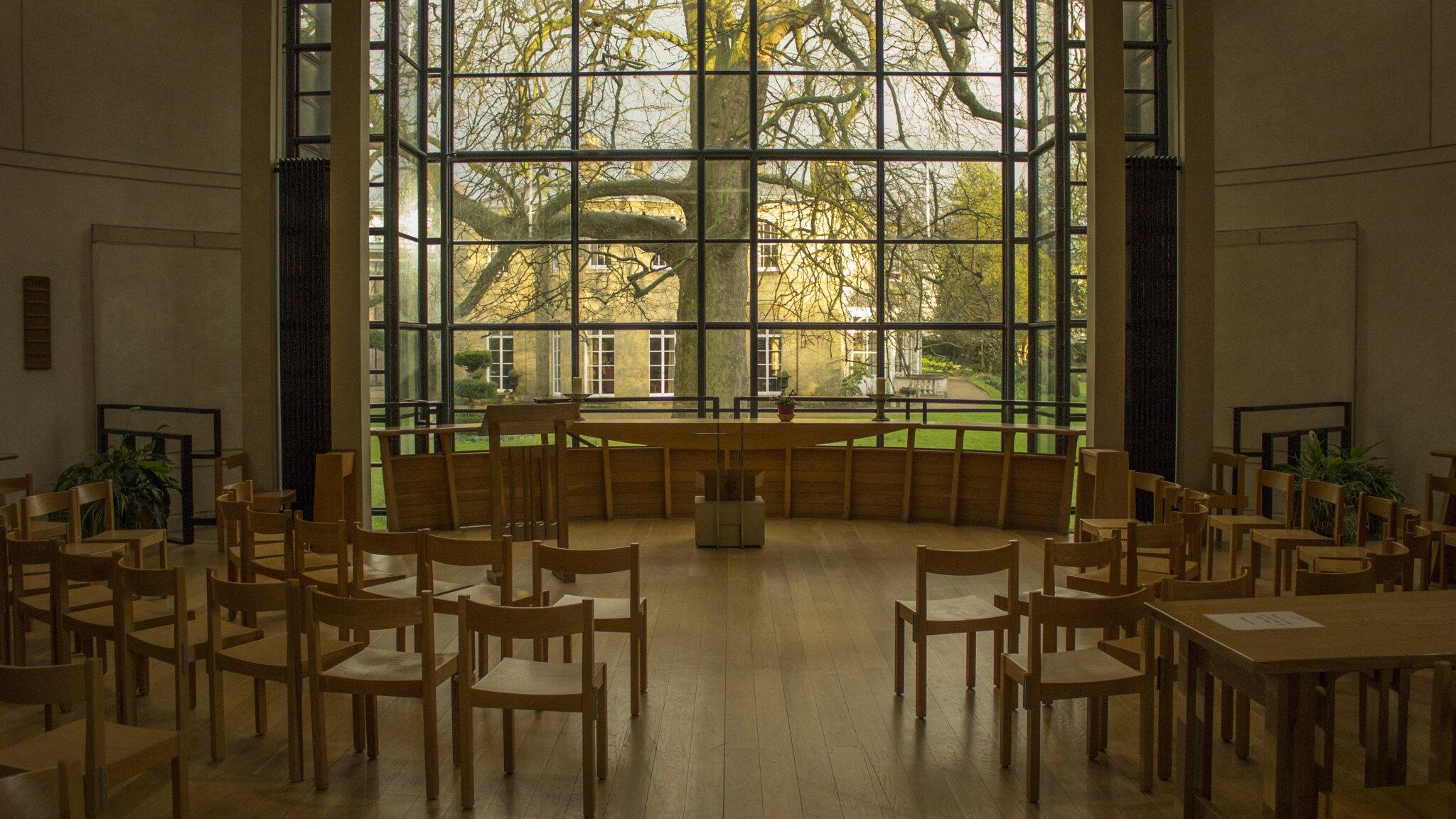 Fitzwilliam College Chapel, photographed by Mihnea Maftei (2016) and licensed for free cultural works (CC BY 3.0) Wooden seating area with window overlooking a large tree