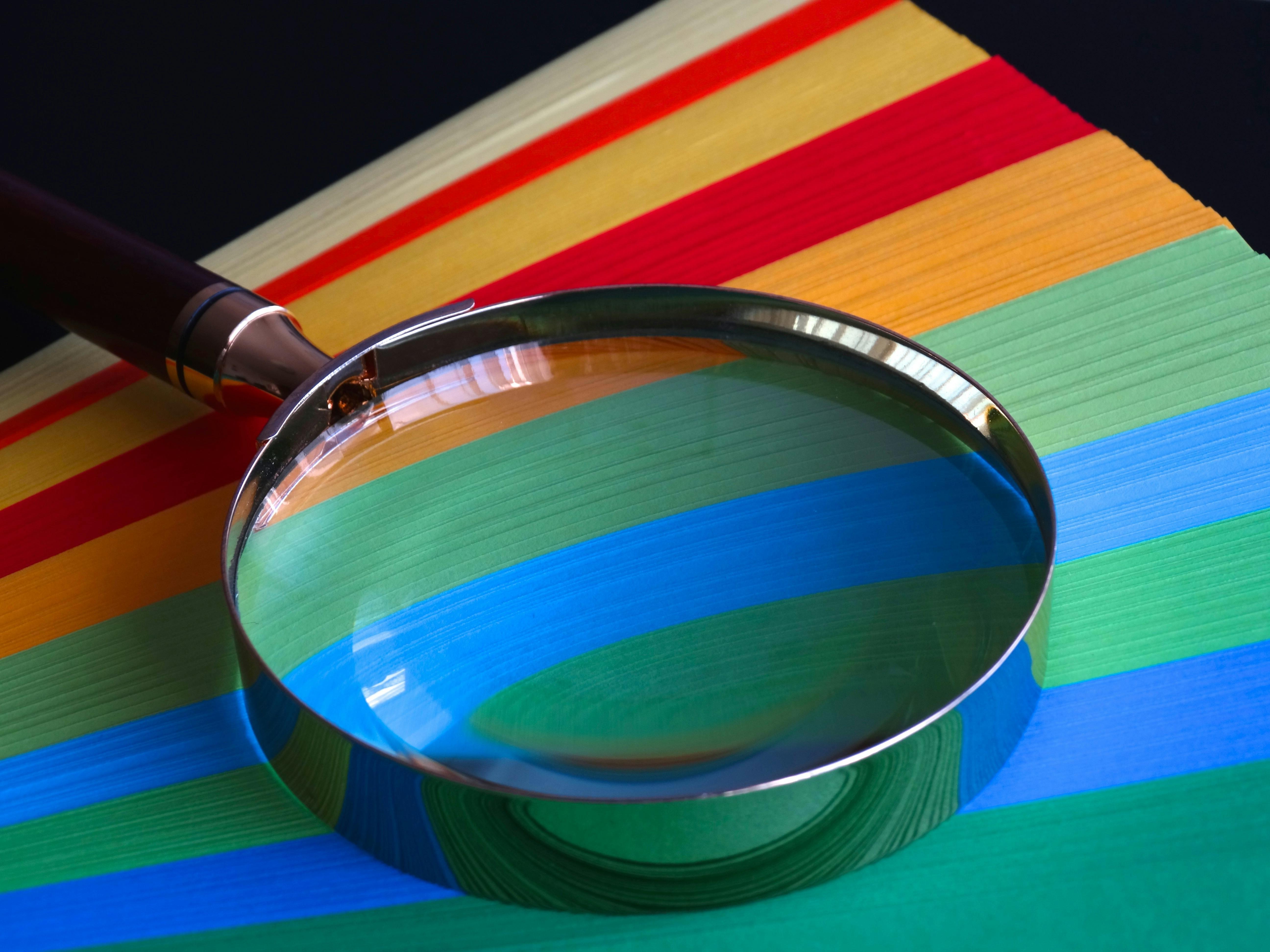 Magnifying glass rests on colourful paper