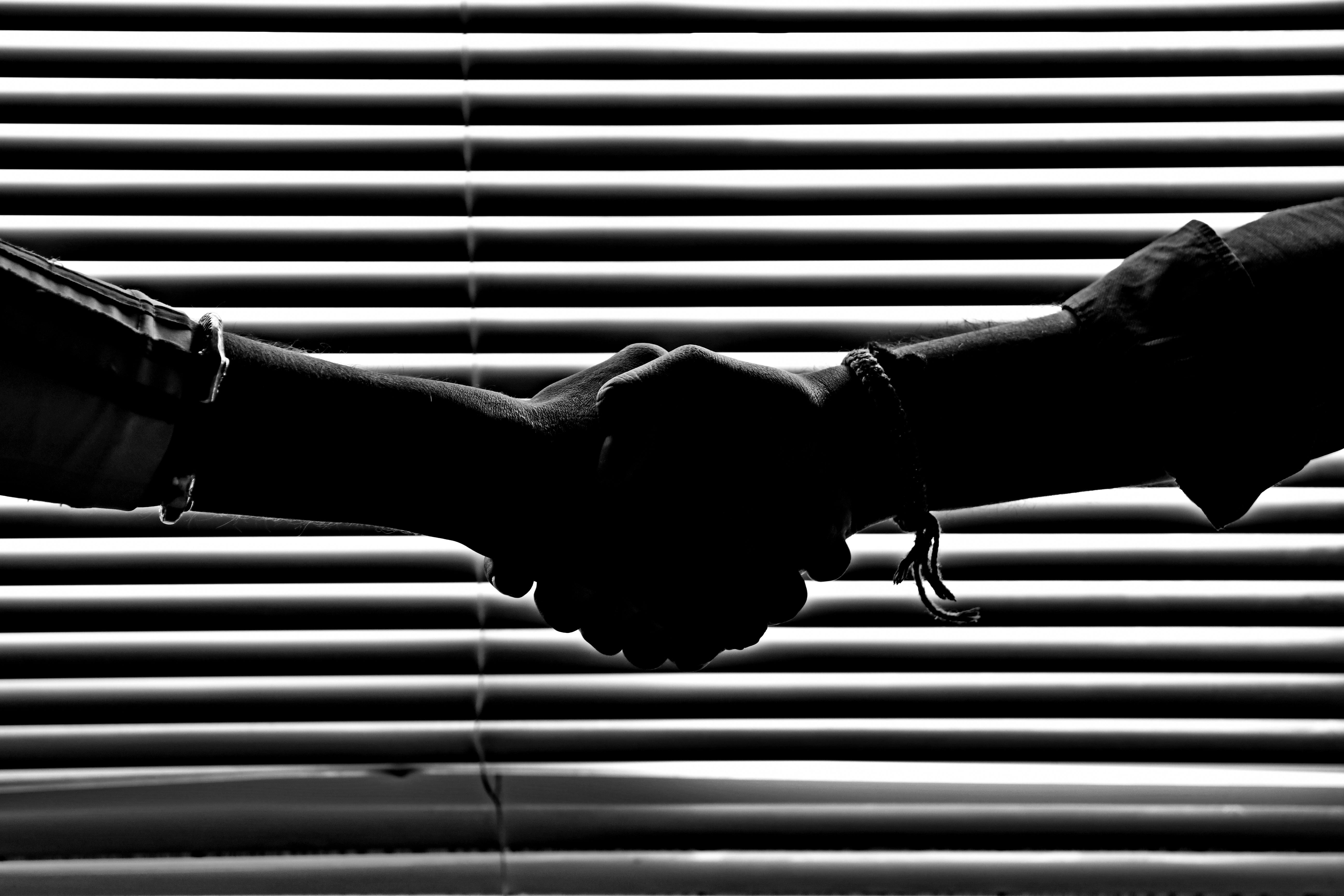 Monochrome image of arms outstretched in handshake