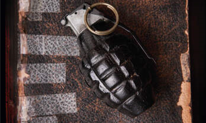 Detail from the cover of Scripture and Violence (ed Snyder and Weiss) A hand grenade sits on top of a book showing signs of disrepair