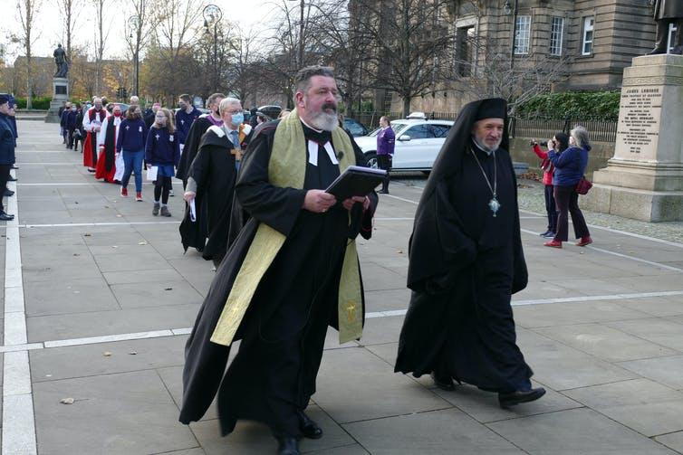 Religious leaders in Glasgow during COP26 - photograph by Tobias Mueller, 2021 (used with permission) A procession of people in diverse religious garments walking towards a building