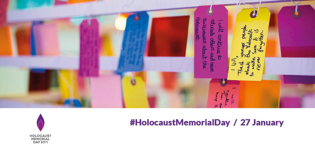 Colourful luggage tags hanging. Each has a handwritten message. Two pledges are legible: "I will, teach younger people about the Holocaust to make sure it is never forgotten. "I will continue to educate others and raise awareness about the Holocaust" 