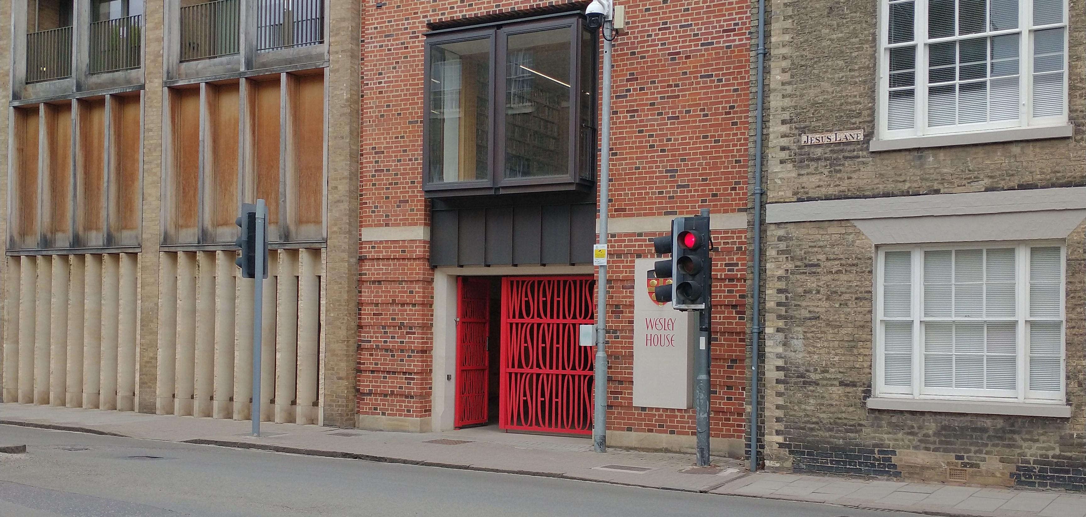 Street scene with red gates repeating the words "Wesley House"